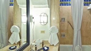 Un baño con lavamanos, espejo, toallero, cortina de ducha y paredes de azulejos.