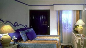 Una habitación de hotel con cama, mesita de noche, lámpara y ventana con cortinas.