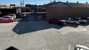 Un parking avec plusieurs voitures et un bâtiment en arrière-plan.