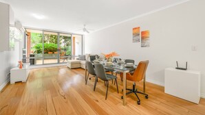 A modern dining area with a glass table, chairs, and a view of the outdoors. - Redfern 2Br Apt with balcony free parking near CBD (Redfern)