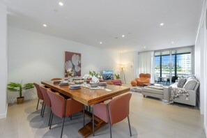 Un salon moderne avec un coin repas, de grandes fenêtres et une vue sur la ville.