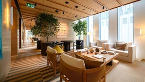 Een moderne hotel lobby met een geruit vloerkleed, houten plafond en grote ramen.