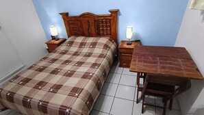 A bedroom with a bed, bedside tables, and a wooden desk.
