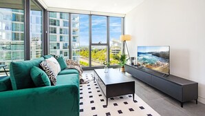 Una sala de estar moderna con un sofá verde, una mesa de centro y un televisor en la pared.