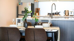 Una cocina moderna con una isla central, electrodomésticos de acero inoxidable y una zona de comedor con una mesa para dos.