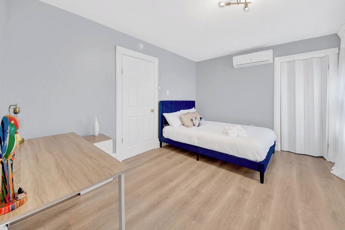 Un dormitorio con cama, escritorio y puerta.