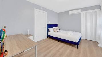 Un dormitorio con cama, escritorio y puerta.