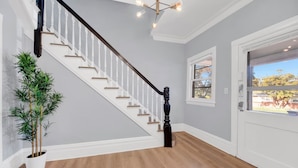 Un escalier avec des balustrades blanches, une plante en pot et une porte donnant sur l’extérieur.