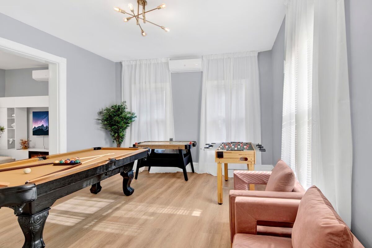 Un salon moderne équipé d’une table de billard, d’un baby-foot et d’un coin salon confortable.