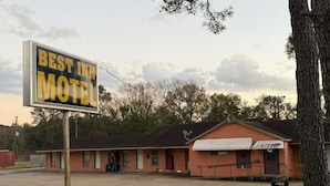 A motel with a sign reading "Best Inn Motel" and a brick building with a red roof.