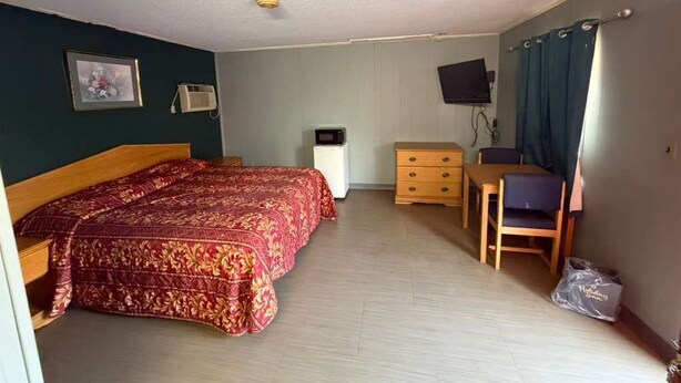 A room with a bed, a desk, a chair, a television, and a picture on the wall.