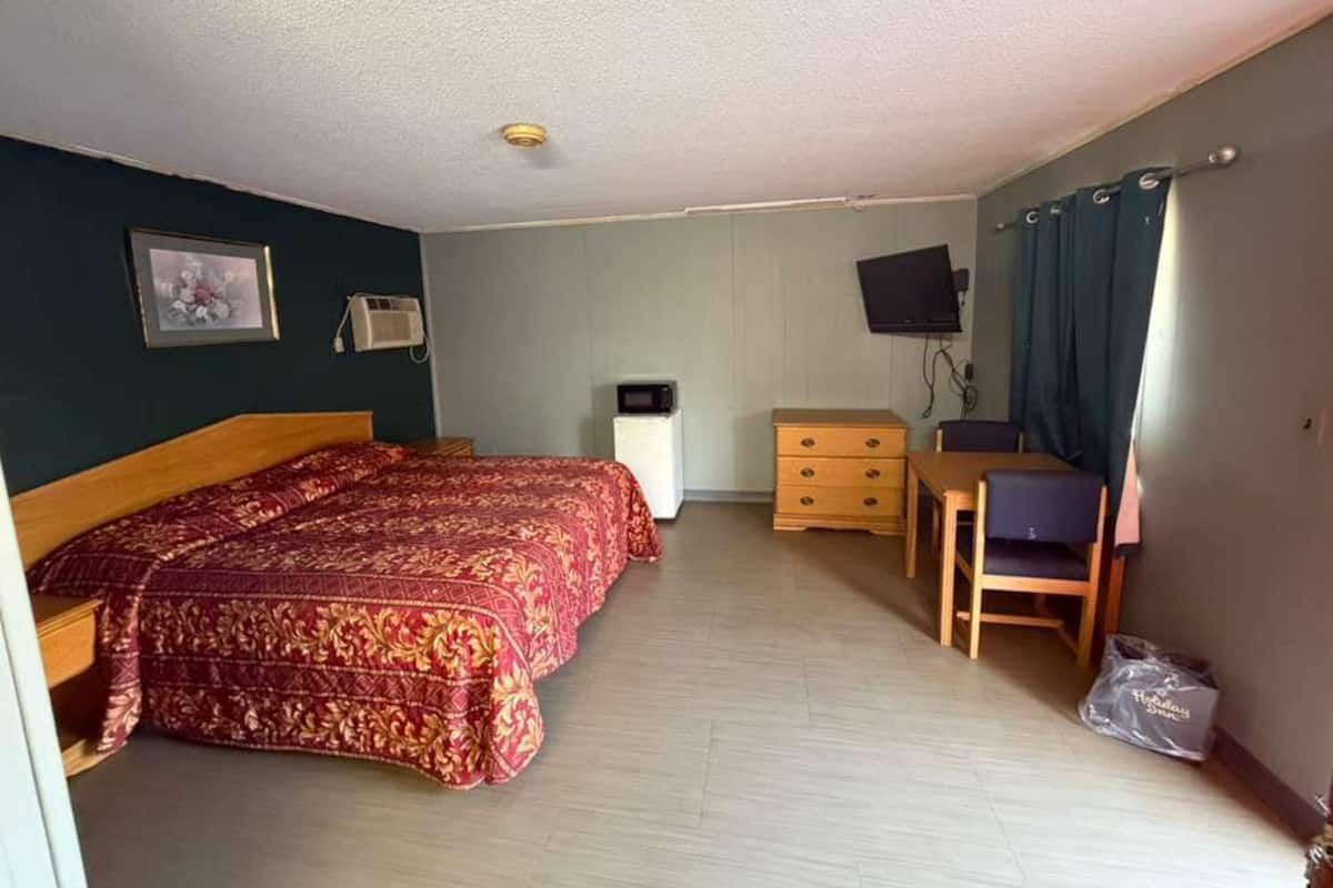 A room with a bed, a desk, a chair, a television, and a picture on the wall.
