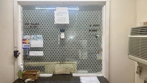 A motel entrance with a chain-link gate, a 'No Visitor' sign, a 'No Pets' sign, and a 'No Refund' sign.
