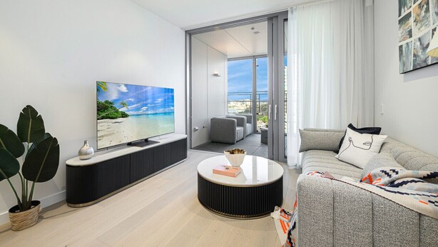A modern living room with a flat-screen TV, a round coffee table, and a sofa. - Waterfront CBD luxury 1Br with best view (Barangaroo)
