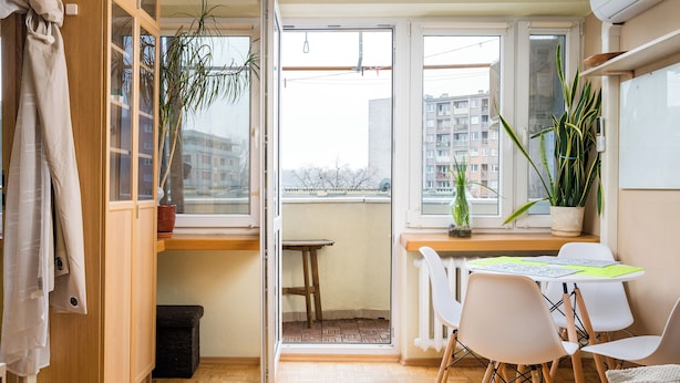 A compact living space with a balcony, wooden flooring, a dining table with chairs, and potted plants. - Solec Powiśle Homely Apartment (Warszawa)