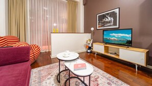 Een woonkamer met een bank, een salontafel, een televisie en een boekenkast.