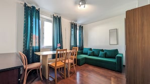 Ein Wohnzimmer mit einem grünen Sofa, einem Holzesstisch und Stühlen.
