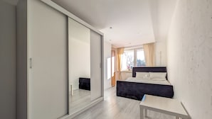 Ein modernes Schlafzimmer mit großem Schiebetürenschrank, einem Bett mit dunklem Kopfteil und einem kleinen Nachttisch.