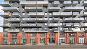 Un edificio moderno de varios pisos con balcones y locales comerciales en la planta baja.