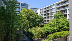 A modern apartment building with multiple balconies and a lush garden area. - Rosebery near Airport & Train & Shops (Rosebery)