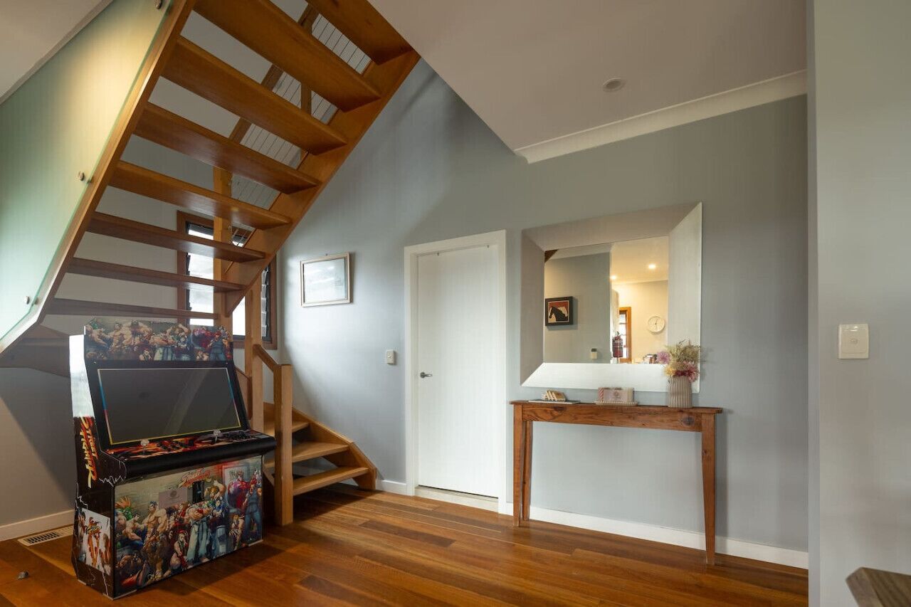 A staircase with wooden beams, a console table with decorative items, and a framed picture on the wall.