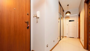 A hallway with wooden doors, a white wall, and a ceiling light. - Częstochowska Urban Comfort Apartment (Łódź)