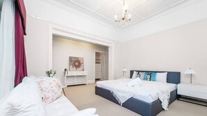 A bedroom with a large bed, a white dresser, a desk, and a chandelier. - Stathfield Stylish 6br house with Pool/Tennis (Strathfield)