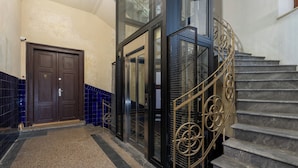 A staircase with a metal railing, a door with a number plate, and a tiled wall. - Świętej Gertrudy Chic Apartment (Kraków)
