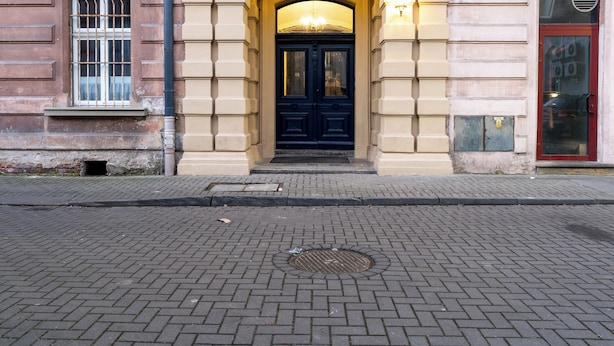 A building entrance with a black door, a small window with bars, and a light fixture above the door. - Świętej Gertrudy Chic Apartment (Kraków)