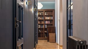 A hallway with a radiator, a door with a handle, and a bookshelf in the background. - Świętej Gertrudy Chic Apartment (Kraków)