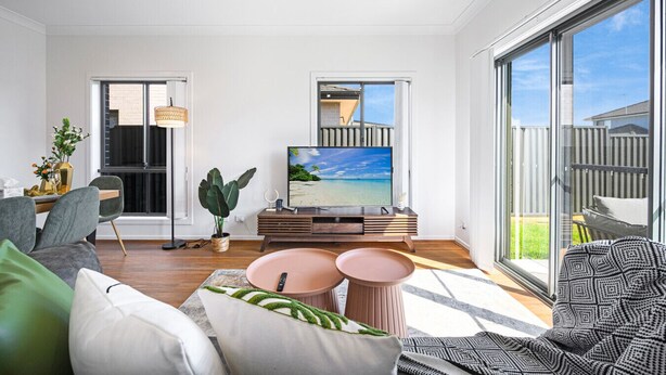 Una sala de estar moderna con un televisor grande, asientos cómodos y ventanas amplias que ofrecen vistas al exterior.