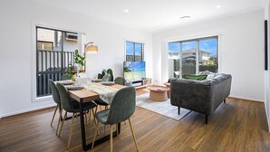 Una sala de estar moderna con comedor, ventanas amplias y vista a una zona residencial.