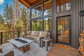 Une cabane moderne dotée d’une grande terrasse, d’un coin salon confortable et d’une cheminée.