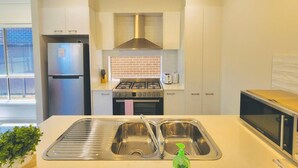 A modern kitchen with stainless steel appliances, a double sink, and a gas stove.