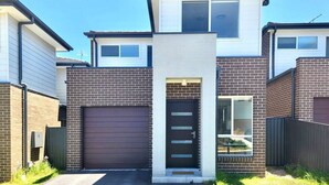 A modern two-story house with a garage, a front door, and a small garden area.