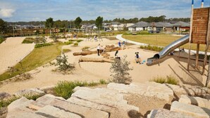 A playground with a slide, swings, and a sandy area.
