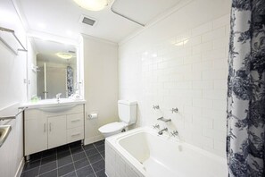 A bathroom with a white sink, toilet, and bathtub, tiled walls, and a mirror. - Sydney CBD 1Br with Spa/Pool/Sauna/Gym by ICC (Pyrmont)