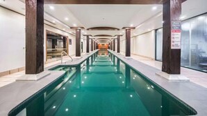 Una piscina interior larga con vista despejada al área de la piscina, pilares de madera y un letrero que indica la profundidad.