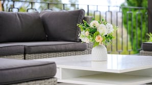 A modern outdoor seating area with a white coffee table and a vase of flowers. - Collaroy 3Br with pool / Breath and Relax (Collaroy)