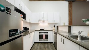 A compact kitchen with white cabinets, a stainless steel refrigerator, a built-in oven, and a sink. - Sydney CBD 1Br with Pool/Spa/Fireworks (Pyrmont)