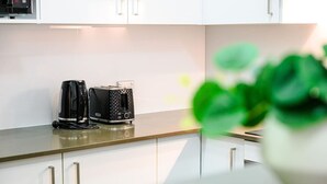 A modern kitchen with a coffee maker, toaster, and a potted plant on the counter. - Sydney CBD 1Br with Pool/Spa/Fireworks (Pyrmont)
