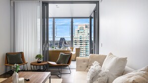 A modern living room with a sofa, chairs, a coffee table, and a view of a cityscape through large windows. - Waterfront CBD luxury 3Br best view & 2 Parkings (Barangaroo)