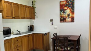 Een keuken met houten kastjes, een magnetron en een eettafel met stoelen.