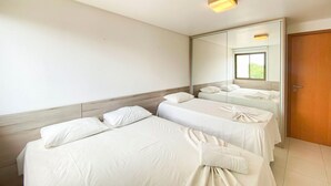 Ein Hotelzimmer mit zwei Betten, einem großen Spiegel und einer Holztür.