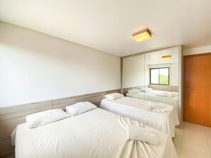A hotel room with two beds, a large mirror, and a wooden door. - Carneiros Beach Resort by CTA (Tamandaré)