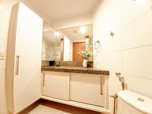 A bathroom with a large mirror, a sink, a toilet, and a shower. - Carneiros Beach Resort by CTA (Tamandaré)
