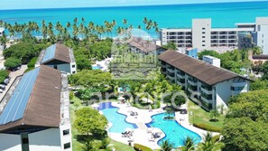 Un resort con piscina, palme e vista sull'oceano.