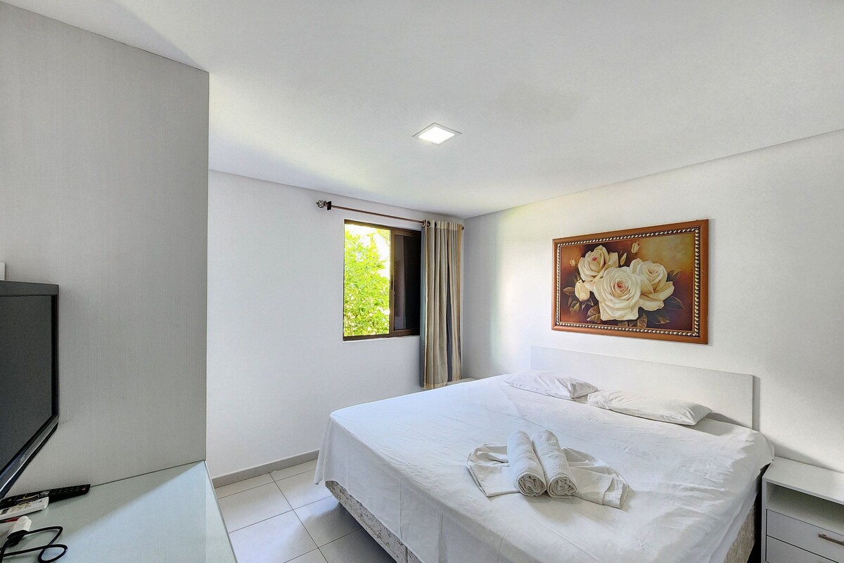 Una camera d'albergo con un letto, un quadro, una finestra e un televisore.