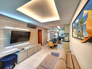 Un soggiorno moderno con TV a schermo piatto, angolo ristoro e cucina completa di microonde.