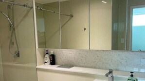 Een moderne badkamer met toilet, douche en wastafel.